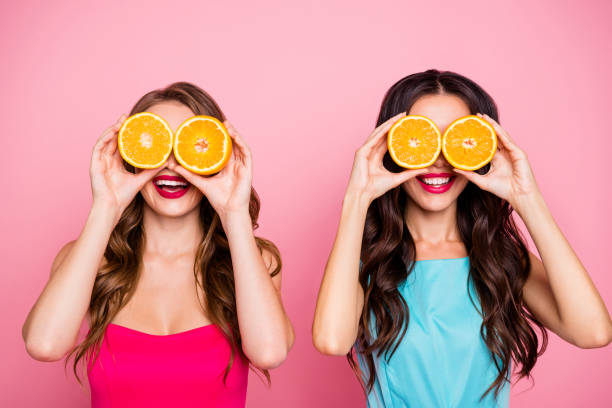 Close up photo two people beautiful she her ladies hands arms hold hide eyes specs organic nature fruits party festive chill hang out wear colorful dresses formal-wear isolated pink bright background Close up photo two people beautiful she her ladies hands arms hold hide eyes specs organic nature fruits party festive chill hang out wear colorful dresses formal-wear isolated pink bright background. oranges with faces stock pictures, royalty-free photos & images