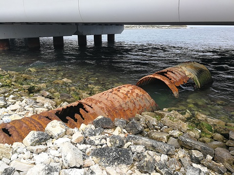 Molfetta, Puglia, Italy - May 19, 2019: Rusty pipelines under the viaduct of the new port under construction
