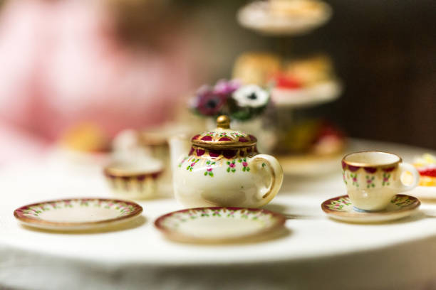Close up color image depicting an old fashioned scene of traditional British afternoon tea in an elegant, high class restaurant. There is a cake stand on the table loaded with cupcakes and sweet treats. In the foreground is old fashioned, elegant crockery - namely, a china teapot and plates. Room for copy space.