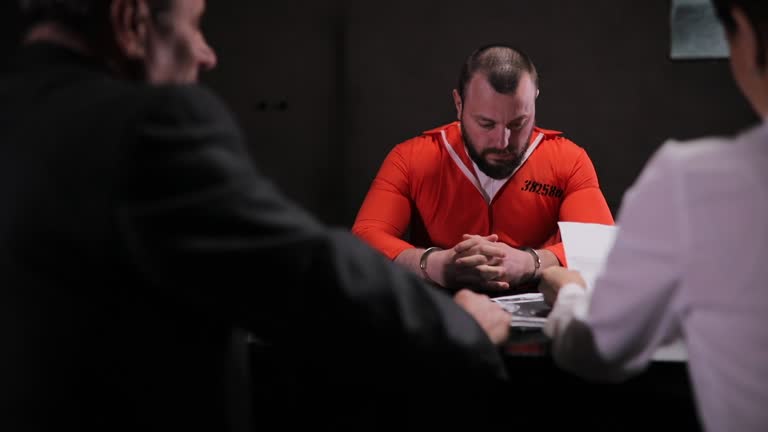 Man and woman detectives interrogating a prisoner in interrogation room