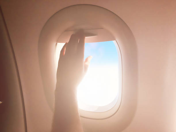 istock Passenger's hand closing the window shade on a modern airplane. 1151962242