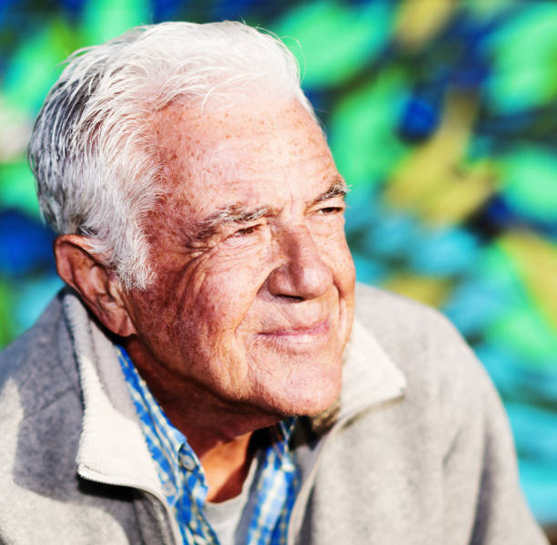 istock Silver-haired senior man with sun-damaged skin squints into the sun 1151963135