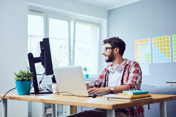istock Creative smiling young man working on his start-up business in cozy home office 1151963847