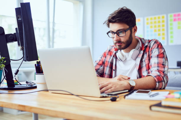 istock Concentrated young man working on laptop at home office 1151964455