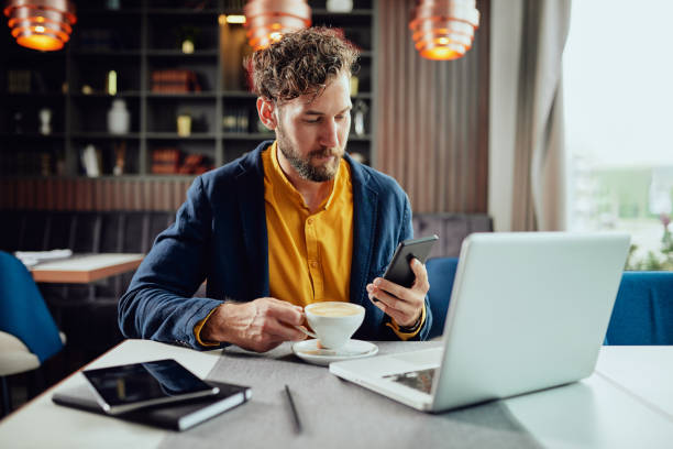 istock Businessman using smart phone and drinking coffee in cafe. 1151968369