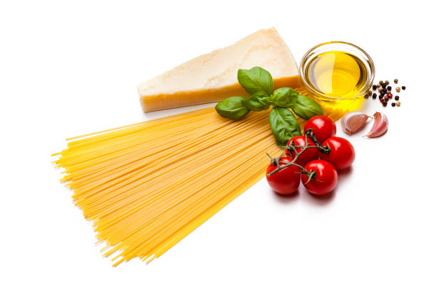 High angle view of ingredients for cooking Italian pasta isolated on white background. The composition includes spaghetti, olive oil, ripe tomatoes, basil, garlic cloves, Parmesan cheese and peppercorns. Predominant color is yellow. High key DSRL studio photo taken with Canon EOS 5D Mk II and Canon EF 100mm f/2.8L Macro IS USM.