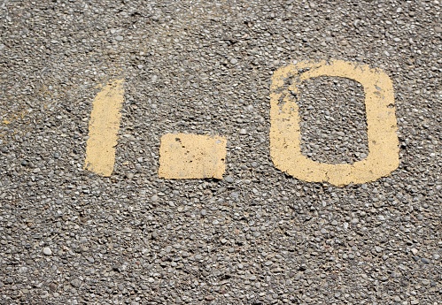 A close view on the yellow painted mile marker on the concrete surface.