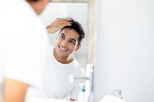 I'm trying a new shampoo and I'm loving the results Cropped shot of a young man touching his hair while looking into the mirror hair care stock pictures, royalty-free photos & images