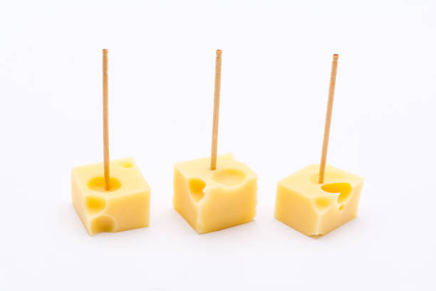 Three cube shape small pieces of yellow cheese with toothpicks on white background Three cube shape small pieces of yellow cheese with toothpicks on white background toothpick stock pictures, royalty-free photos & images