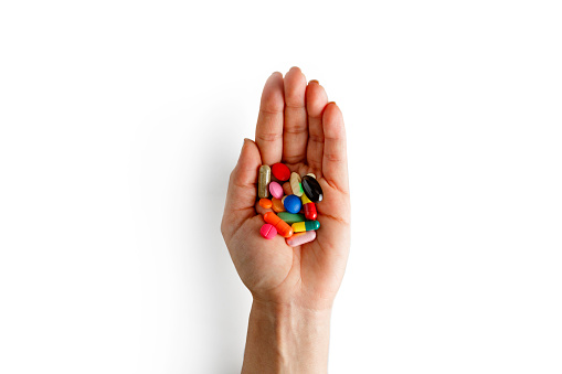 Health themes. Assorted multicolored pills and capsules on female hand