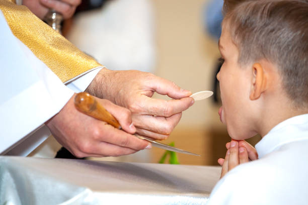 priest gives first communion. symbol of the body and blood of christ - color image jesus christ child people imagens e fotografias de stock