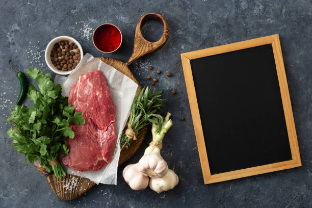 istock Food menu Cooking table with blank chalk board and beef meat, vegetables, spices, herbs top view 1151978731