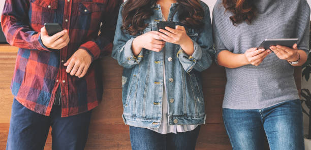 istock Three young asian people using and looking at mobile phone and tablet pc together 1151980369