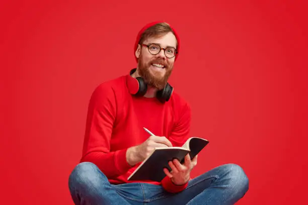 Photo of Smiling hipster writing in notebook