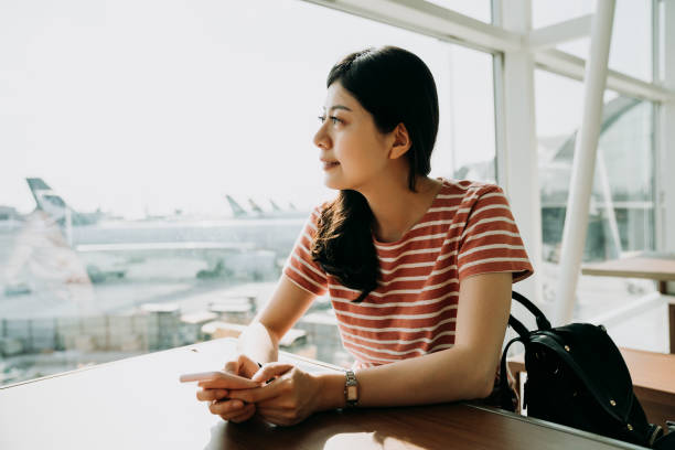 istock woman holding mobile phone waiting for her flight 1151982183
