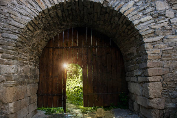 Dark medieval open wood doorway to summer secret garden Old wooden open door. Dark medieval woods doorway to summer light secret garden old stone wall stock pictures, royalty-free photos & images