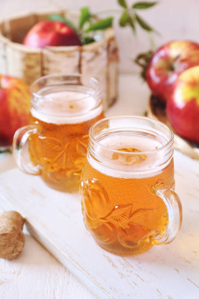 Two cups of Apple Cider and red apples in wooden  basket on light background