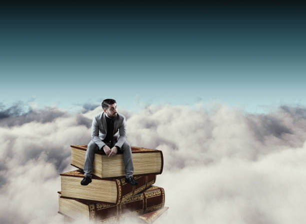 istock Businessman on a tower of books above clouds. 1151987653