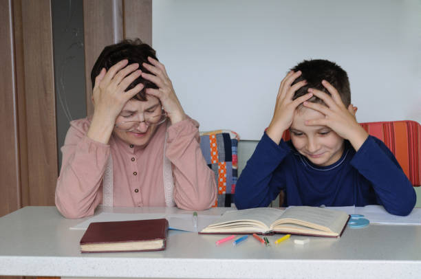 istock Grandmother helps her grandson to perform school homework. 1151989010