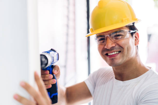 istock Young construction worker working with screwdriver to drill in a house entrance 1151991938