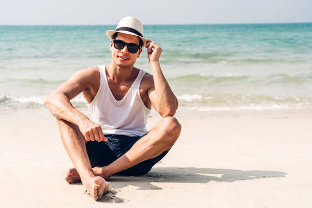 Smiling handsome man relax in sunglasses and straw hat on the tropical beach.Summer vacations stock photo