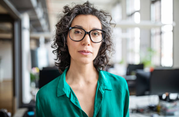 Portrait of mature businesswoman in office Portrait of mature businesswoman in casuals standing in office. Close-up of confident female entrepreneur looking at camera. one mature woman only stock pictures, royalty-free photos & images