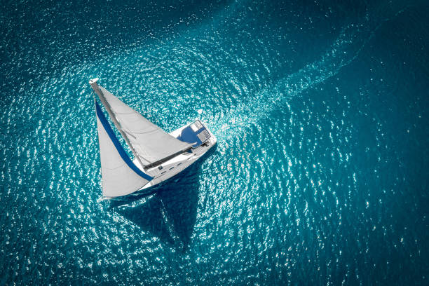 Regatta sailing ship yachts with white sails at opened sea. Aerial view of sailboat in windy condition Regatta sailing ship yachts with white sails at opened sea. Aerial view of sailboat in windy condition. sailboat stock pictures, royalty-free photos & images