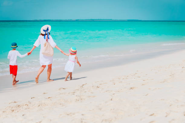 istock mother and two kids walking on beach 1151994562