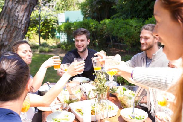 istock Cheerful young people sitting at table and toasting juice 1151999118