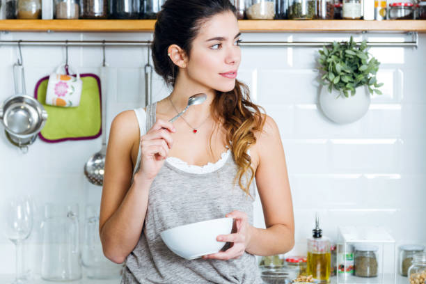 Portrait of beautiful young woman having breakfast in the kitchen.
