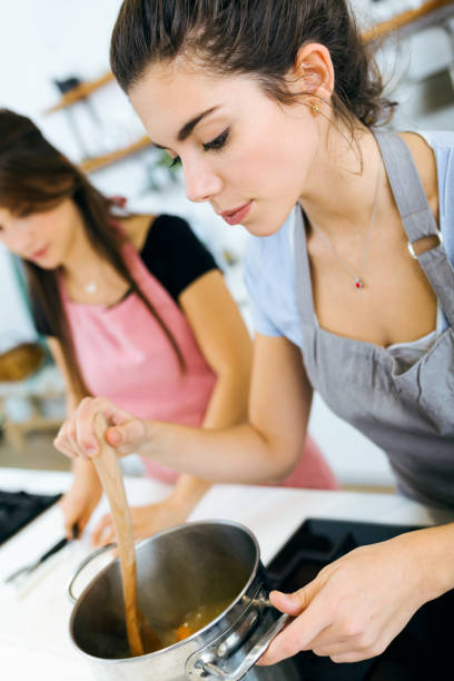istock Two beautiful women cutting and cooking fresh vegetables in kitchen. 1152001548