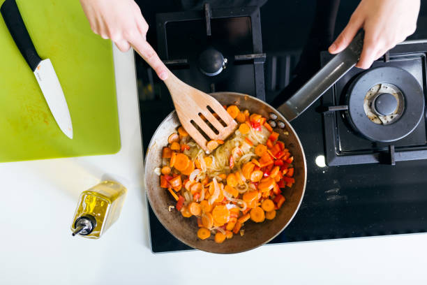 istock Young woman frying vegetables into the pan. 1152001880