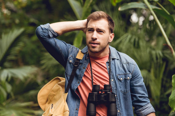 istock handsome tense traveler with binoculars and backpack in green tropical forest 1152002408