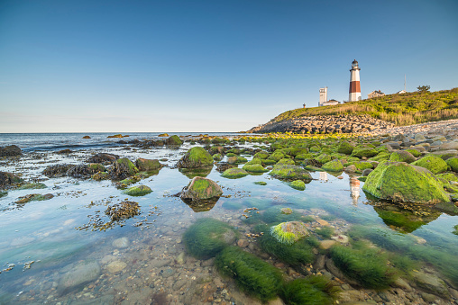 A panorama view of the Penmon Lighthouse in North Wales with relfections in a tidal pool