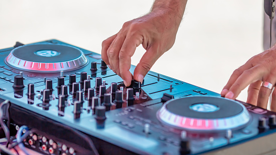DJ mixing tracks on professional DJ sound controller at outdoor music festival