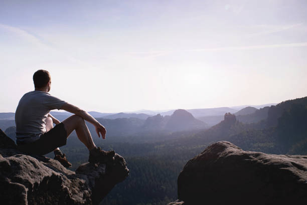 istock Thinking man sit on rock. Man on exposed summit watching 1152006690