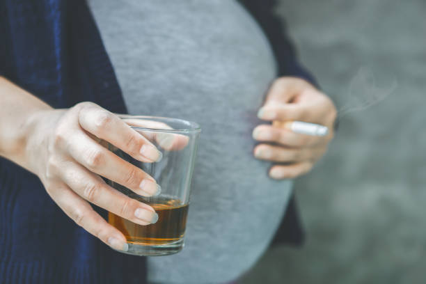 careless pregnant asian woman hand drinking glass of alcohol and smoking cigarette - nicotine healthcare and medicine smoking issues lifestyles imagens e fotografias de stock