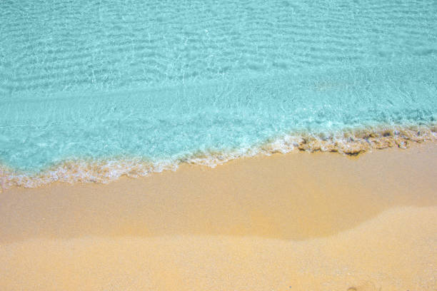 Soft wave of turquoise sea water on the sandy beach.