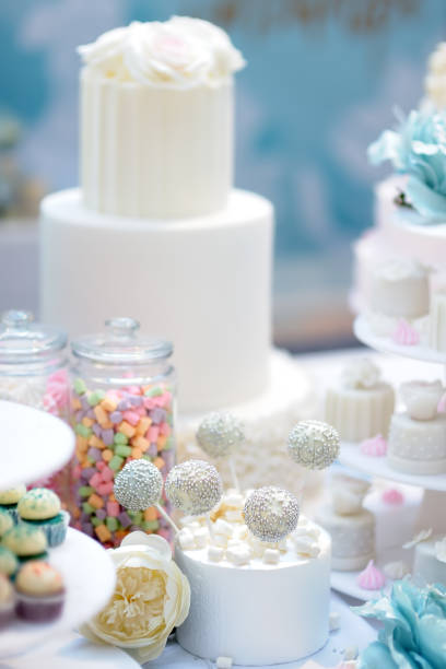 istock Traditional anniversary/wedding multi-layer cake decorated with flowers. And beautiful delicious sweet dessert - cupcakes, marshmallow, vanilla cake pops. 1152016095