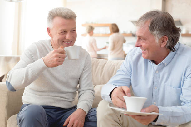 istock Smiling mature men holding coffee while sitting on sofa at home 1152017989