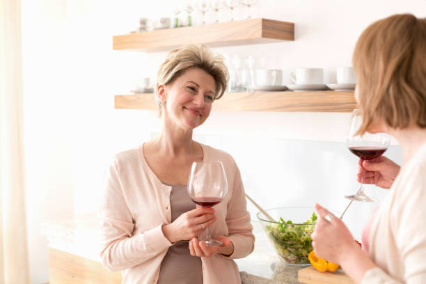 istock Smiling mature women holding wineglasses while standing in kitchen 1152019357