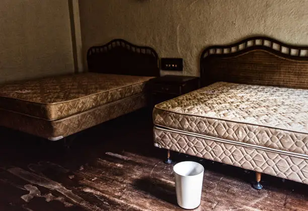 Interior view of a room with a couple of beds in an abandoned building.