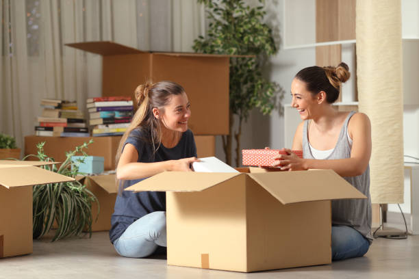 Roommates talking unboxing gelongings moving home Roommates talking unboxing gelongings moving home tenant stock pictures, royalty-free photos & images