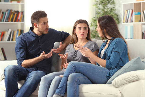 trois amis sérieux parlant s’asseyant sur un divan à la maison - speech talking teenager student photos et images de collection