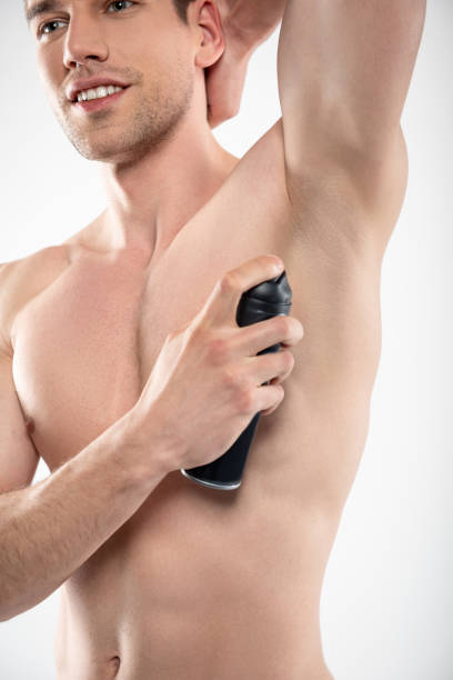 istock Handsome young man with perfect body using deodorant spray 1152026360