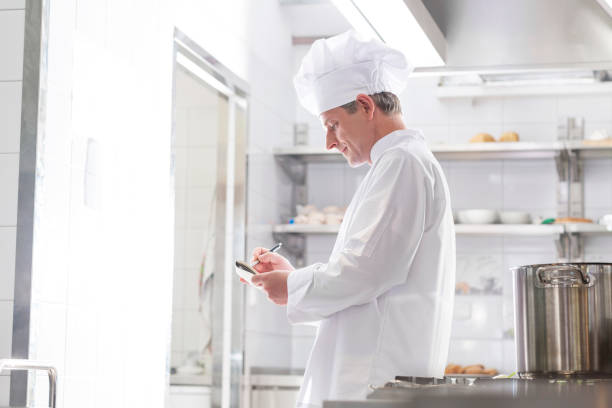 istock Side view of chef writing on notepad while standing in kitchen at restaurant 1152027013