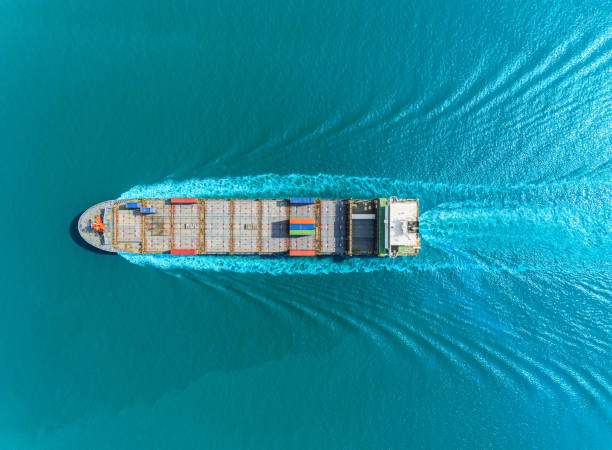 Aerial top view container ship full speed with beautiful wave pattern on the blue sea for logistics, import export, shipping or transportation.