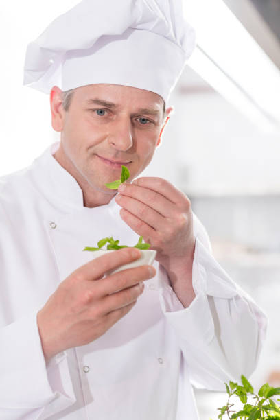 istock Confident mature chef smelling herb leaves in kitchen at restaurant 1152029352