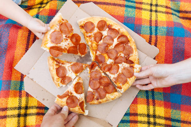 Hands take slices of pepperoni pizza, food delivery, picnic
