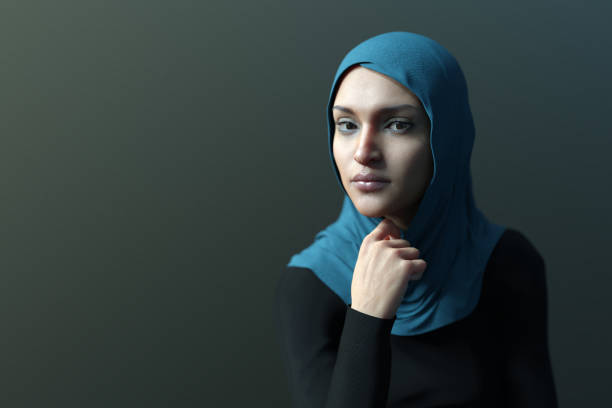 Close up of a young Iranian woman wearing a hijab looking at the camera on green background. Side view.